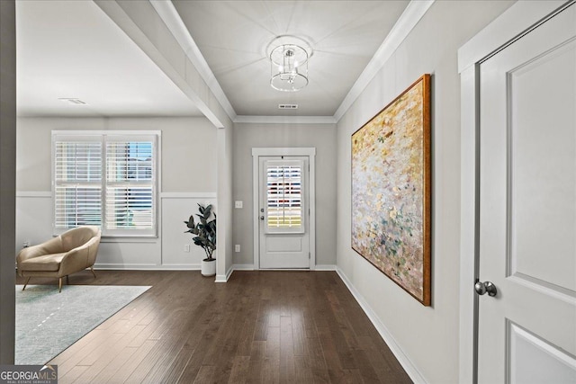 foyer entrance featuring dark wood-style flooring, baseboards, an inviting chandelier, ornamental molding, and visible vents