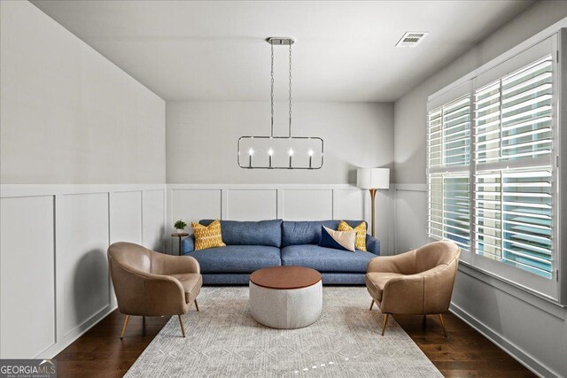 interior space with a notable chandelier, a wainscoted wall, dark wood-type flooring, visible vents, and a decorative wall