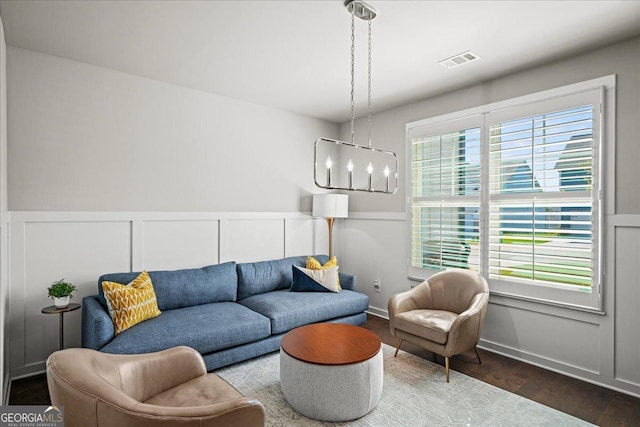 living area featuring wood finished floors, a wainscoted wall, visible vents, and a decorative wall
