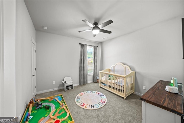 carpeted bedroom featuring visible vents, baseboards, a ceiling fan, and a crib