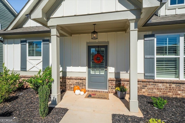 view of exterior entry with a shingled roof, board and batten siding, and covered porch