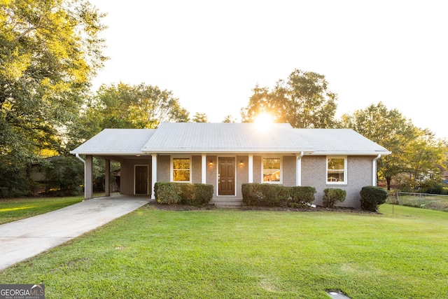 single story home featuring driveway, fence, a front yard, a carport, and brick siding