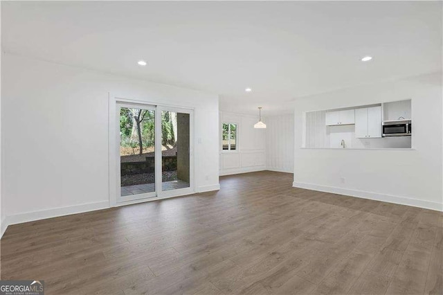 unfurnished living room featuring recessed lighting, wood finished floors, and baseboards