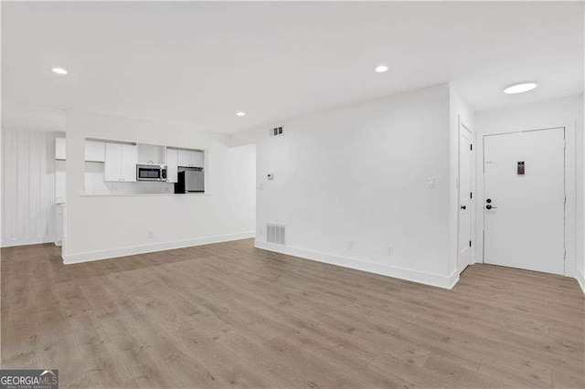 unfurnished living room featuring light wood-type flooring, visible vents, baseboards, and recessed lighting