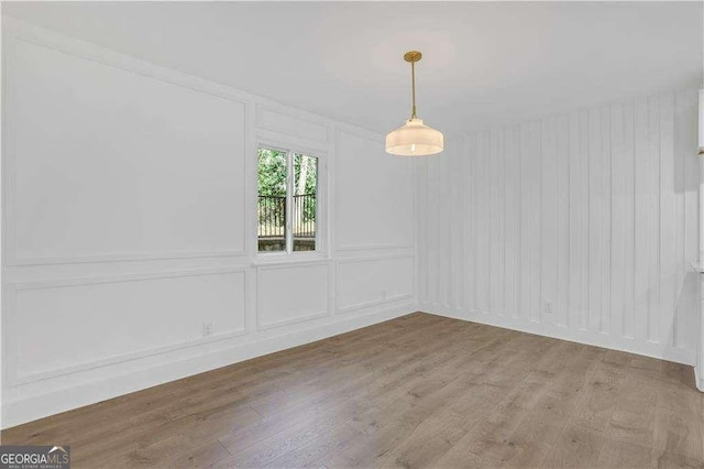 empty room with a decorative wall and light wood finished floors