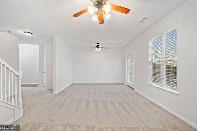 unfurnished room featuring light carpet, stairway, visible vents, and baseboards