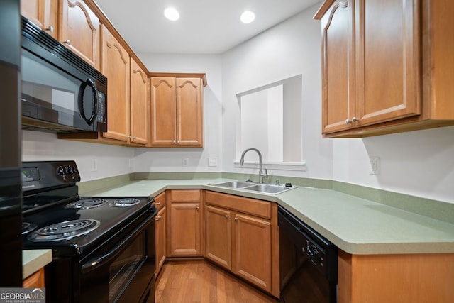 kitchen featuring black appliances, light countertops, a sink, and recessed lighting