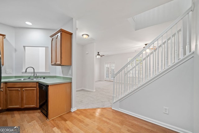 kitchen with black dishwasher, a ceiling fan, light wood-style flooring, open floor plan, and a sink