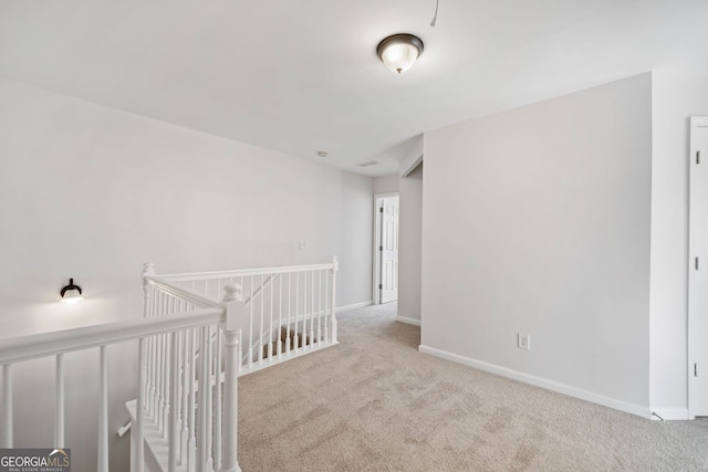 interior space with light carpet, baseboards, and an upstairs landing