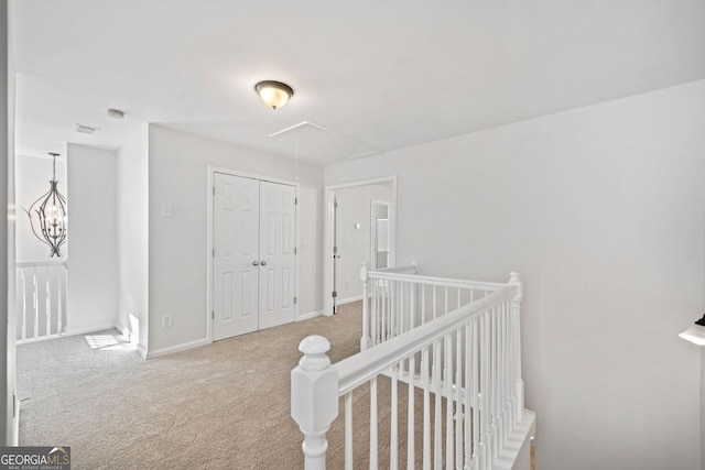 hall with carpet, attic access, baseboards, and an upstairs landing