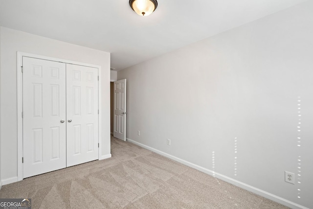 unfurnished bedroom with baseboards, a closet, and light colored carpet