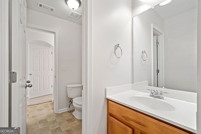 bathroom with toilet, vanity, visible vents, and baseboards