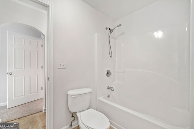 bathroom featuring toilet, baseboards, and shower / washtub combination