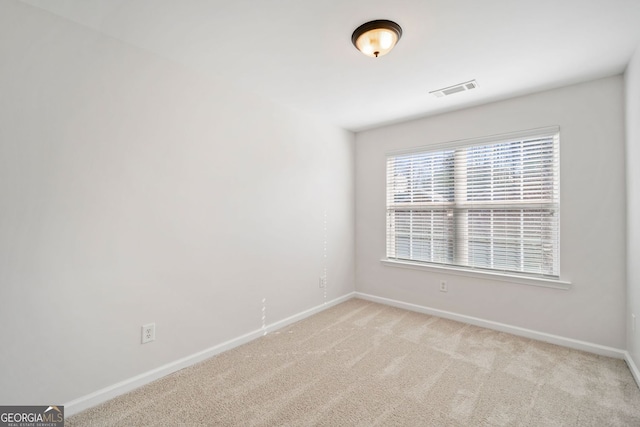 empty room featuring baseboards, visible vents, and light colored carpet