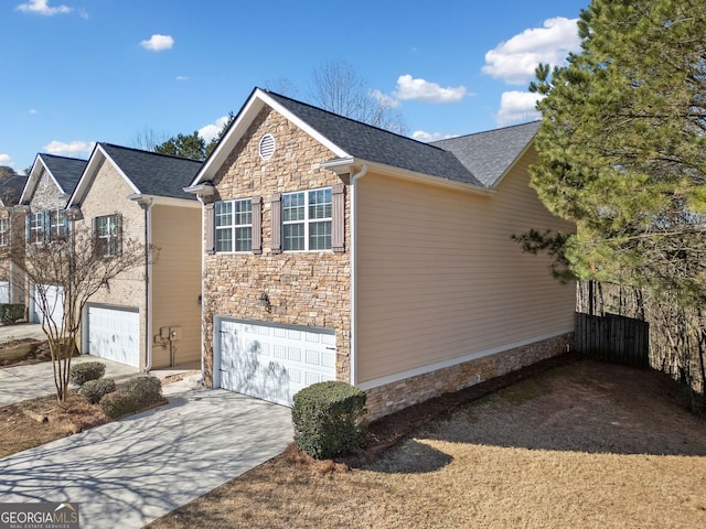 view of side of home featuring a garage, stone siding, and driveway