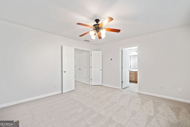 unfurnished bedroom featuring light colored carpet, visible vents, ensuite bath, and baseboards