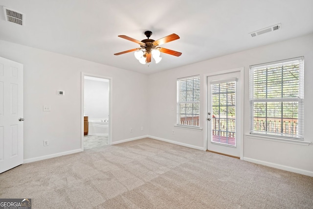 spare room with light carpet, visible vents, and baseboards