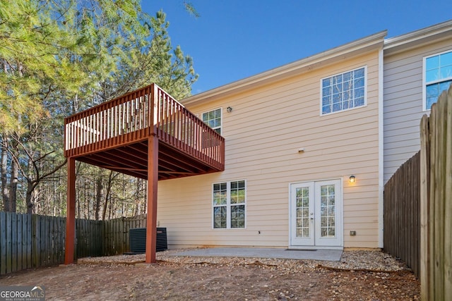 rear view of property with a deck, a fenced backyard, cooling unit, french doors, and a patio area