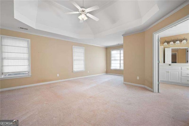 unfurnished bedroom with ornamental molding, a tray ceiling, light carpet, and visible vents