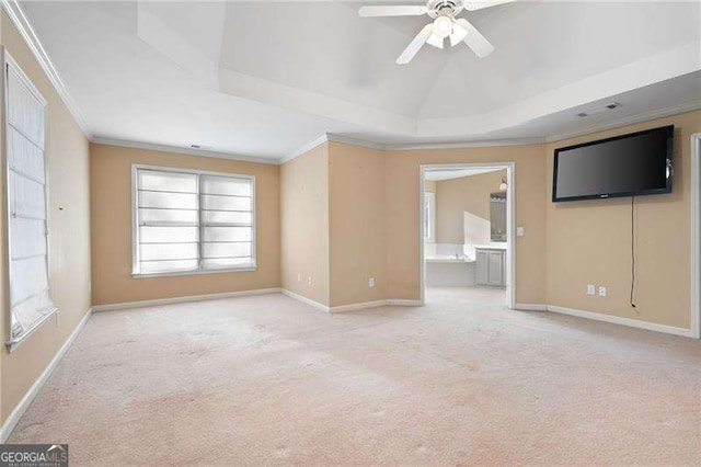 spare room featuring ornamental molding, a tray ceiling, light carpet, and baseboards