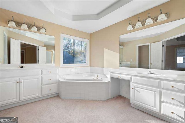 full bathroom featuring a tray ceiling, vanity, and a bath