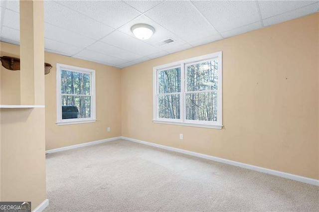 spare room featuring a paneled ceiling, carpet flooring, visible vents, and baseboards