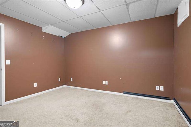 empty room with a paneled ceiling, light carpet, and baseboards