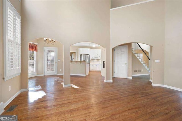 foyer with baseboards, arched walkways, and dark wood finished floors