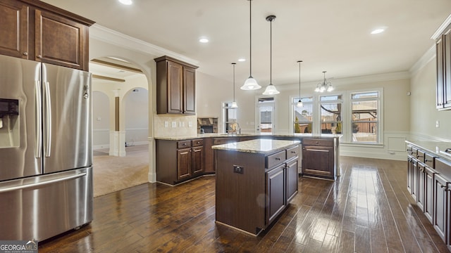 kitchen with stainless steel fridge, arched walkways, a peninsula, crown molding, and a sink