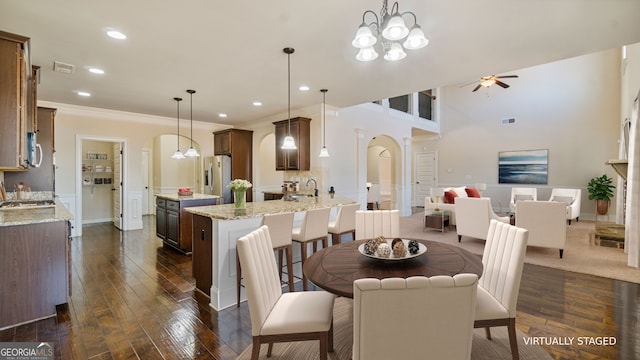 dining room with crown molding, arched walkways, visible vents, and dark wood finished floors