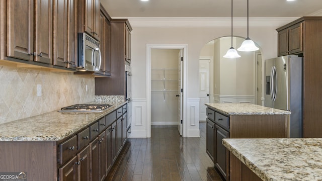 kitchen with tasteful backsplash, dark wood finished floors, ornamental molding, stainless steel appliances, and dark brown cabinets