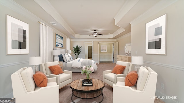 carpeted living room featuring ornamental molding, a tray ceiling, baseboards, and a ceiling fan