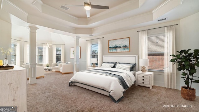 bedroom featuring light carpet, decorative columns, visible vents, and a tray ceiling