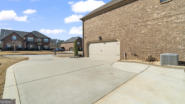 view of home's exterior featuring cooling unit, a garage, brick siding, driveway, and a residential view