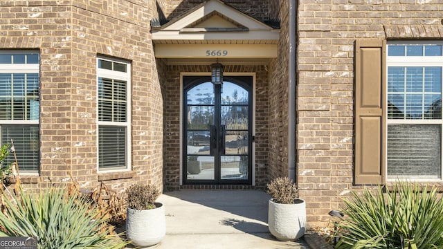 property entrance featuring french doors and brick siding