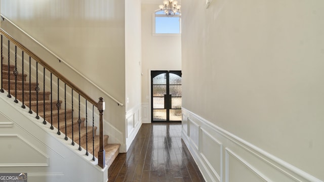 foyer with a chandelier, a healthy amount of sunlight, a decorative wall, and dark wood-type flooring