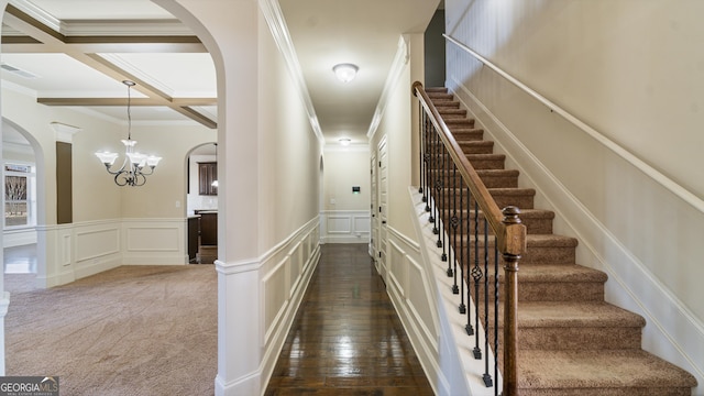 staircase featuring carpet floors, arched walkways, visible vents, a decorative wall, and coffered ceiling