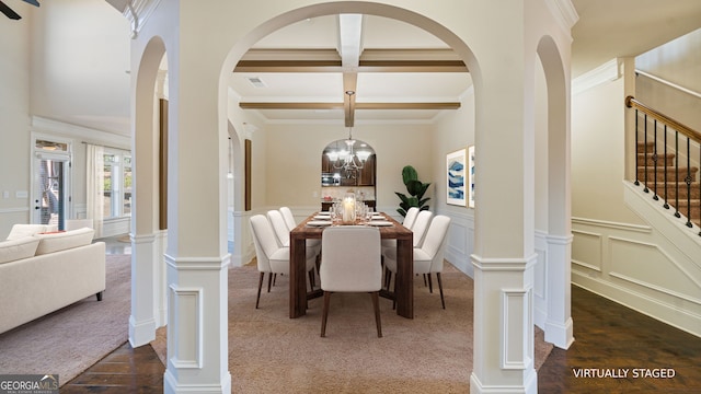 dining space featuring a decorative wall, coffered ceiling, visible vents, stairs, and beamed ceiling