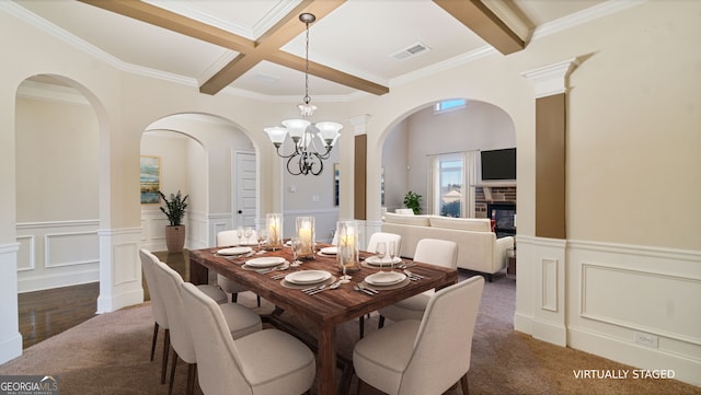 dining space featuring visible vents, coffered ceiling, a glass covered fireplace, wainscoting, and beamed ceiling