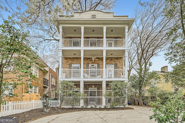 view of front of home featuring a balcony, fence, and brick siding