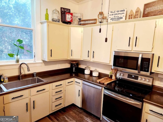 kitchen with dark countertops, dark wood-style floors, stainless steel appliances, white cabinetry, and a sink