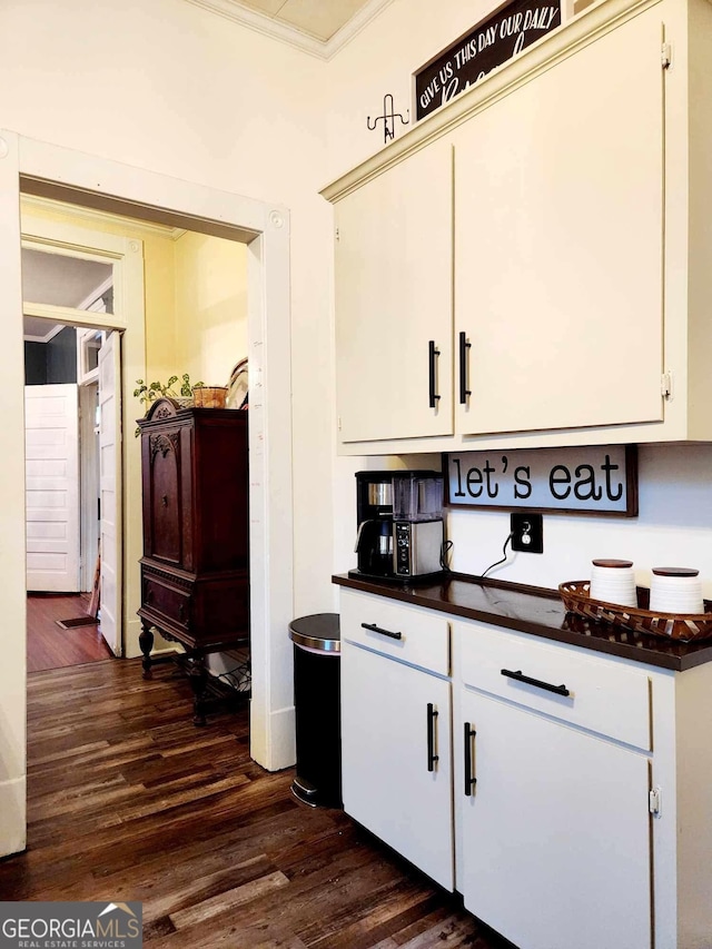 bar featuring ornamental molding and dark wood finished floors