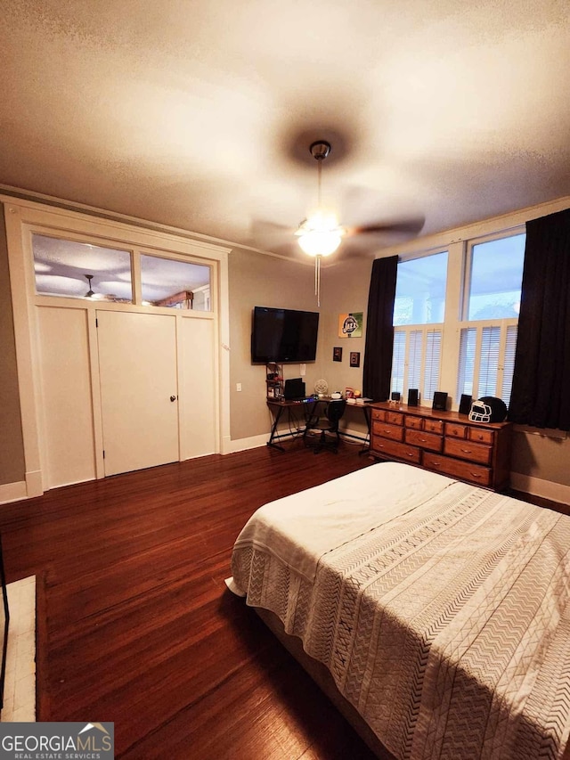 bedroom with dark wood-style floors, ceiling fan, and baseboards