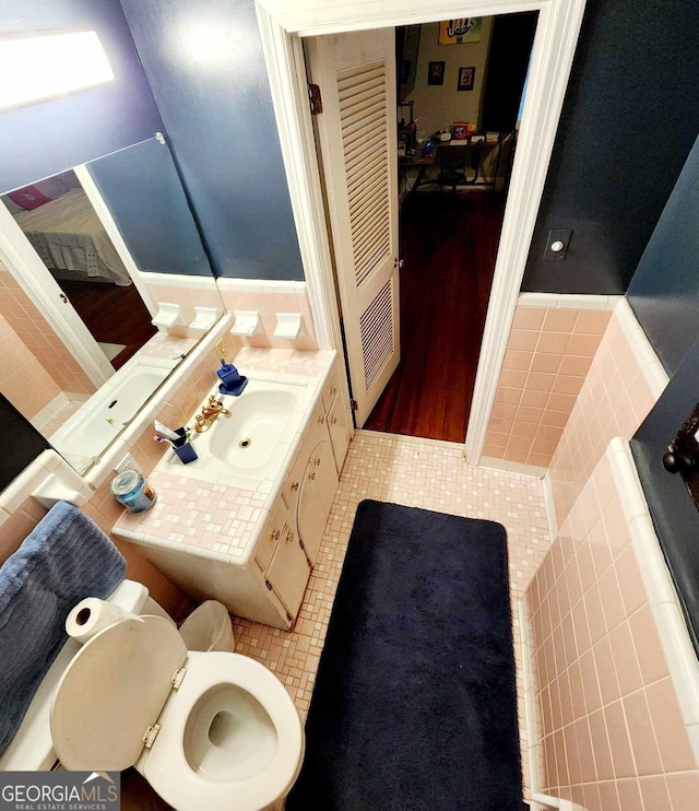 bathroom with tile walls, vanity, and toilet