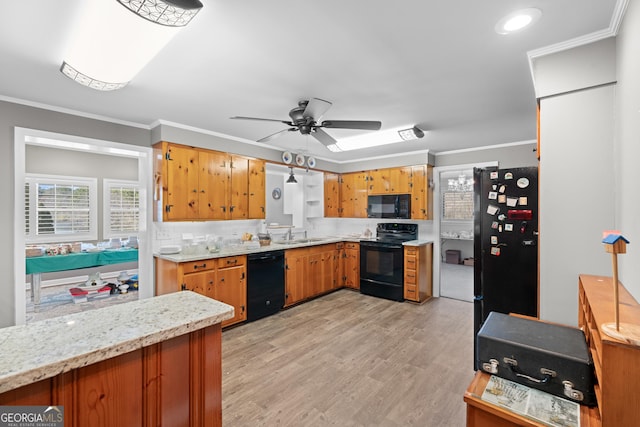 kitchen with black appliances, ornamental molding, brown cabinetry, and light wood-style floors