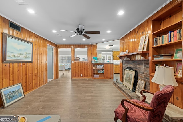 living room featuring wood walls, light wood-type flooring, visible vents, and crown molding