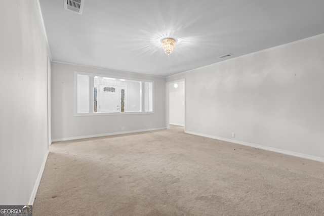 empty room featuring light colored carpet, visible vents, crown molding, and baseboards