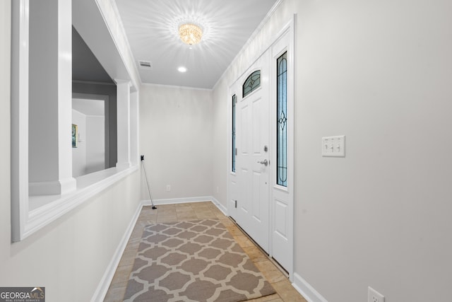 foyer entrance with baseboards, visible vents, and crown molding