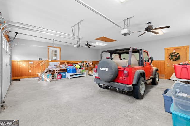 garage with a wainscoted wall, ceiling fan, and a garage door opener