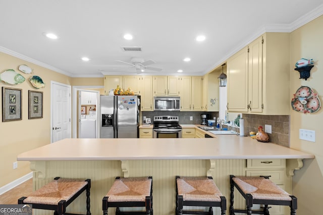 kitchen featuring light countertops, visible vents, appliances with stainless steel finishes, washer / dryer, and a kitchen breakfast bar